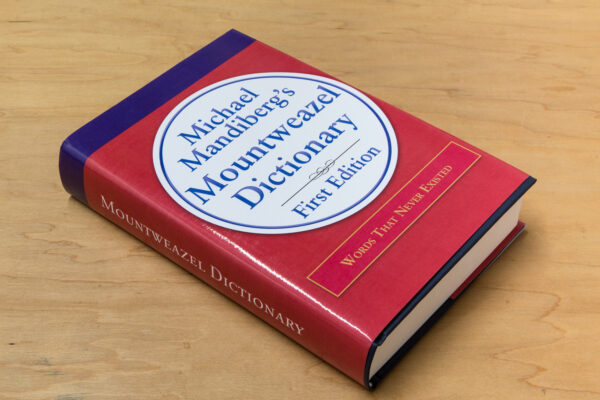 A large hardbound book with a red cover on a maple wood table